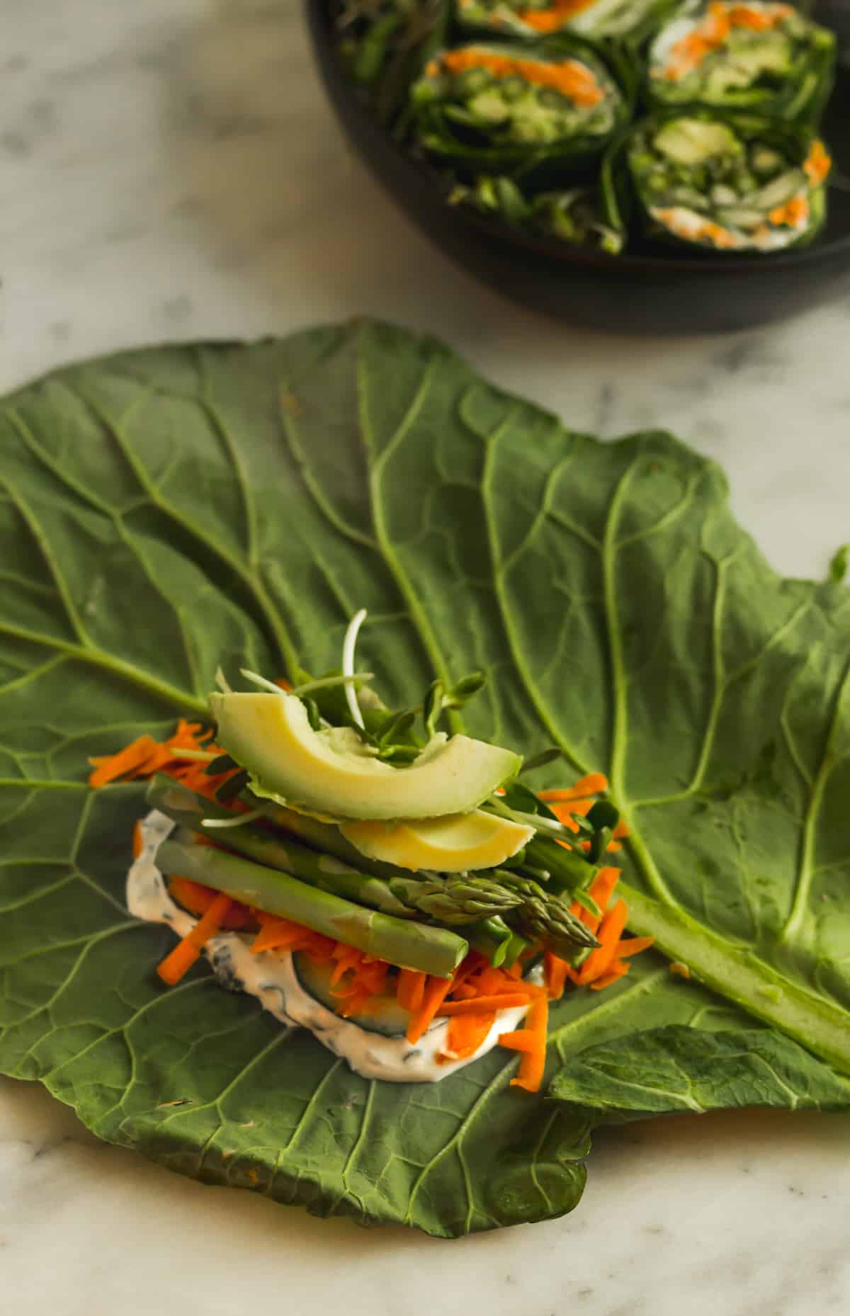 Large collard green leaf stuffed with veggies and whipped feta before it is rolled up