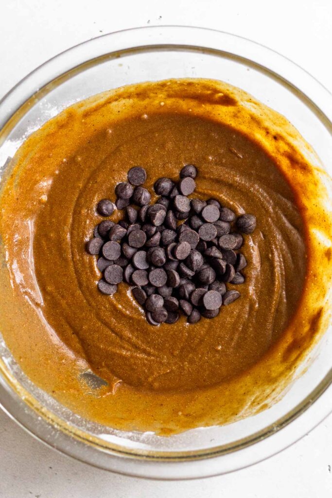 Batter in a glass bowl with chocolate chips on top of it.
