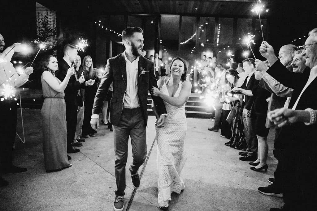 A man and women walking through a line of people holding sparklers after they got married