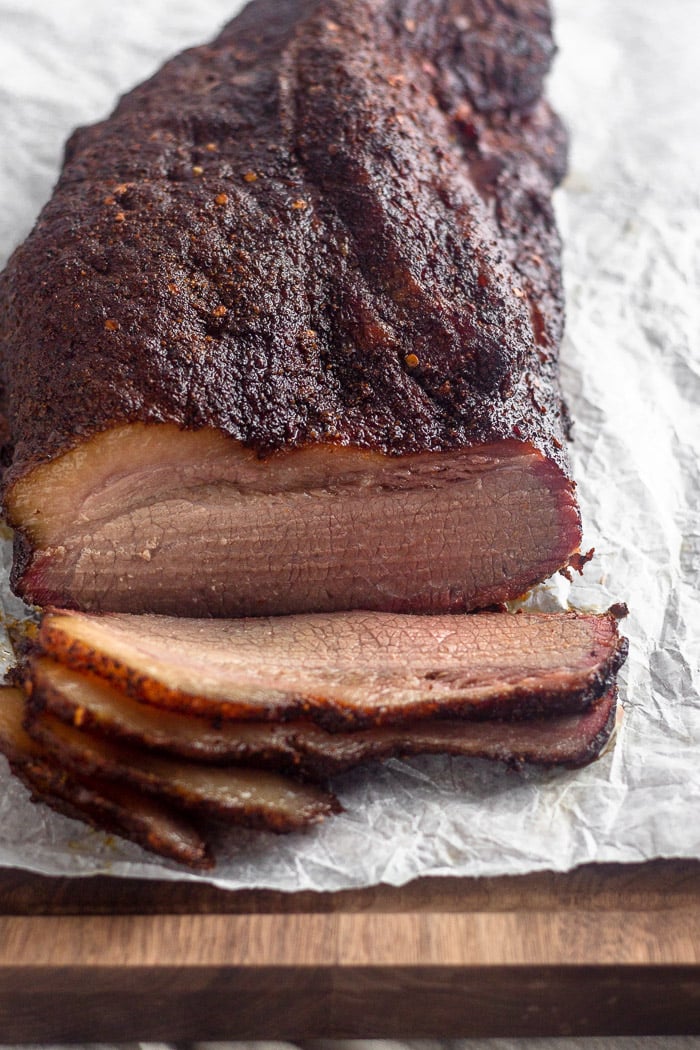 Smoked brisket sitting on a cutting board with a free pieces cut from it