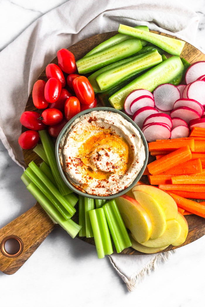 A platter of veggies with a bowl of cauliflower hummus in the middle.
