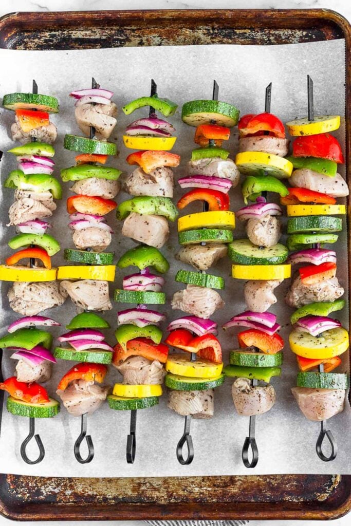 Chicken and veggies on metal skewers before they are cooked.