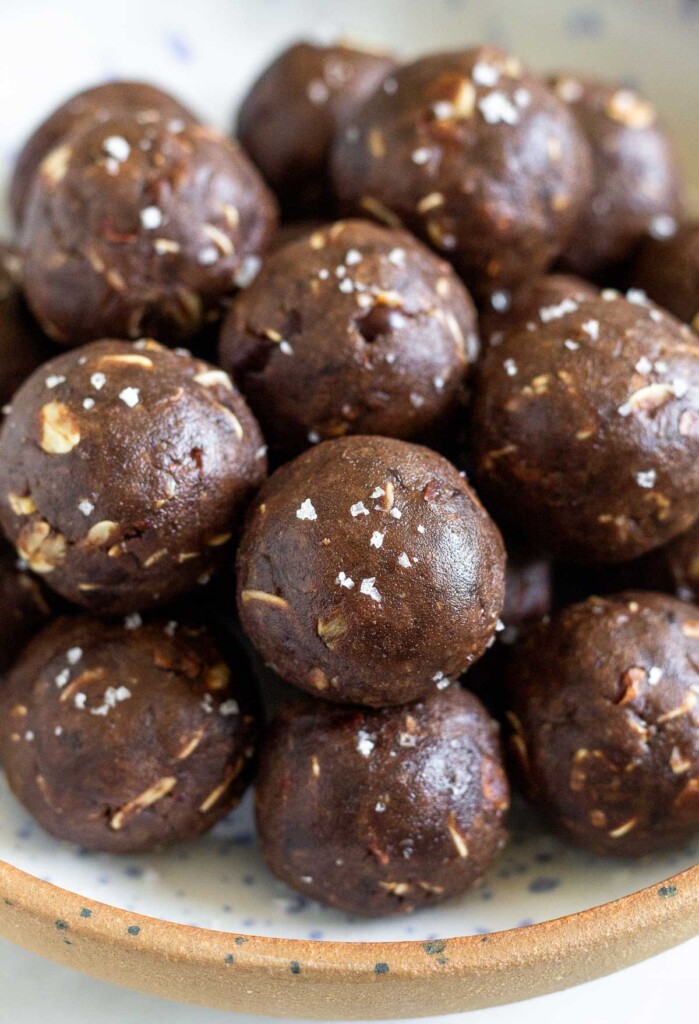 A bowl of chocolate peanut butter protein balls. They are sprinkled with sea salt.