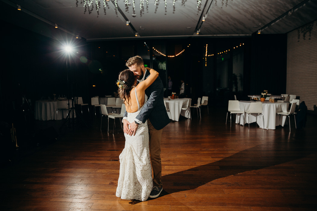 Bride and groom doing a last dance by themselves in an empty room. The groom's hands are on the bride's butt.