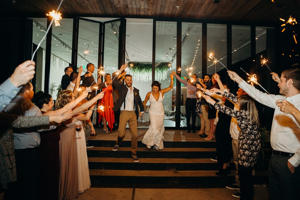 Bride and groom walking through a line of people on both sides with sparklers.