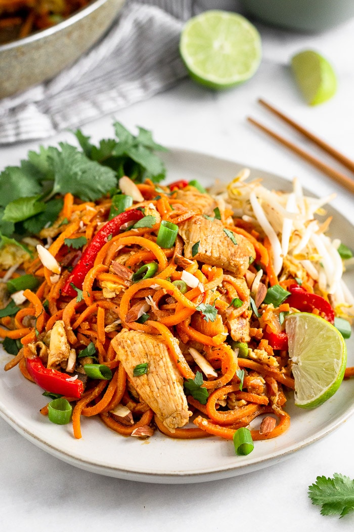 Whole30 chicken pad thai on a plate with a lime wedge and cilantro.