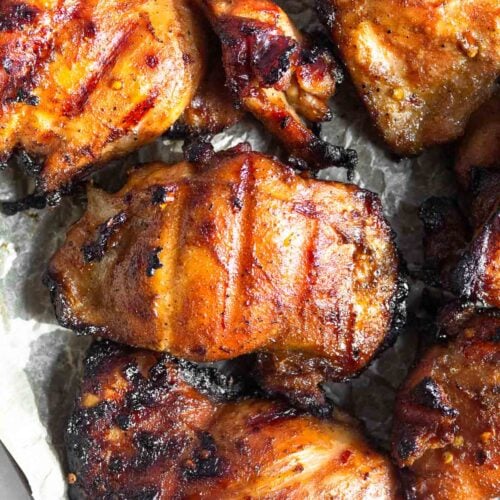 Overhead shot of grilled marinated chicken thighs on a baking sheet.