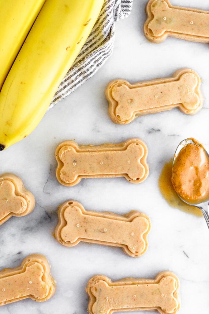 Overhead shot of a few homemade peanut butter dog treats shaped as bones.