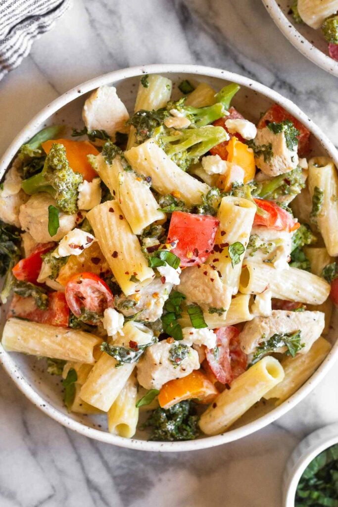 Goat cheese pasta in a bowl topped with fresh herbs.