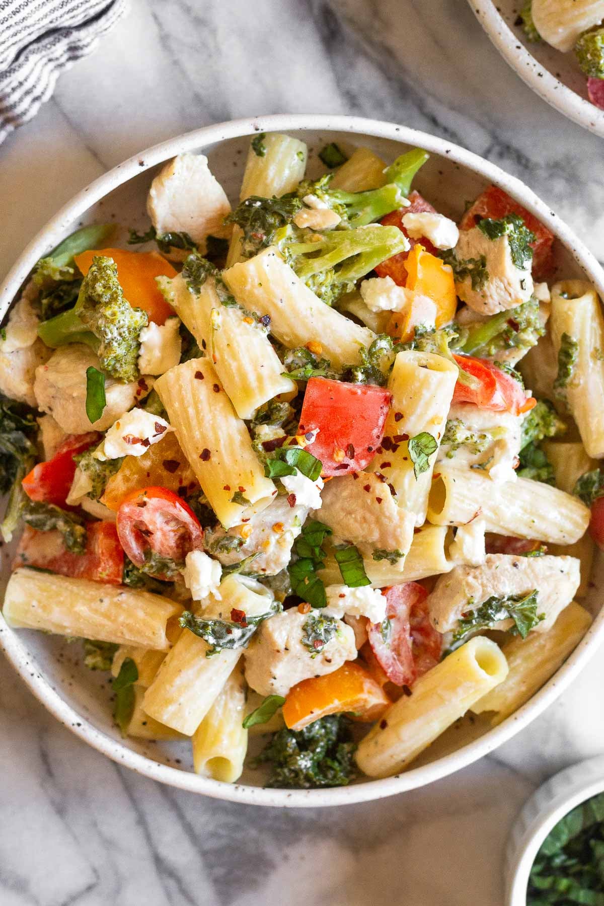 Goat cheese pasta in a bowl topped with fresh herbs.