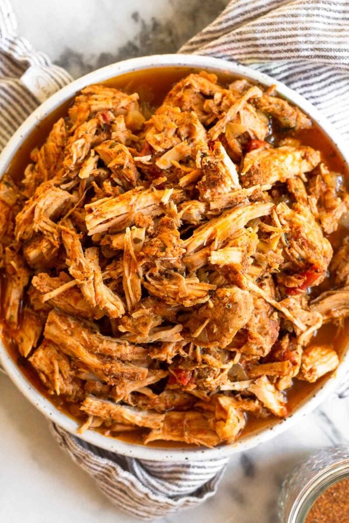 Shredded crockpot pot pork chops on a plate sitting on a stripped towel.