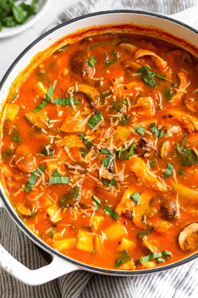 High protein soup with chicken and veggies in a tomato broth topped with fresh herbs and parmesan cheese.