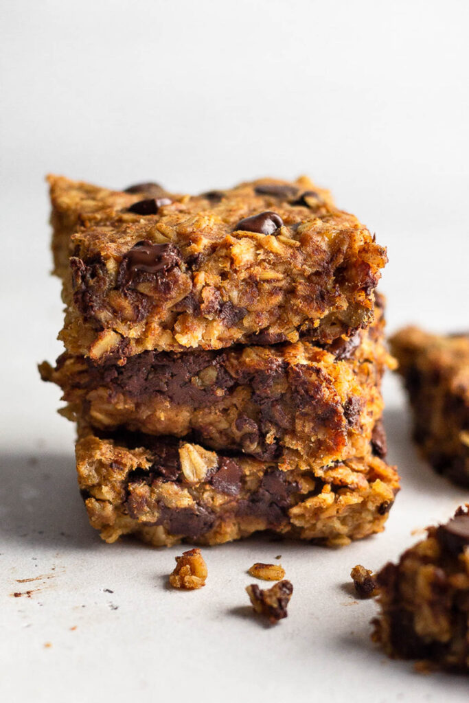Three oatmeal chocolate chip bars stacked on top of each other with two more off to the side.