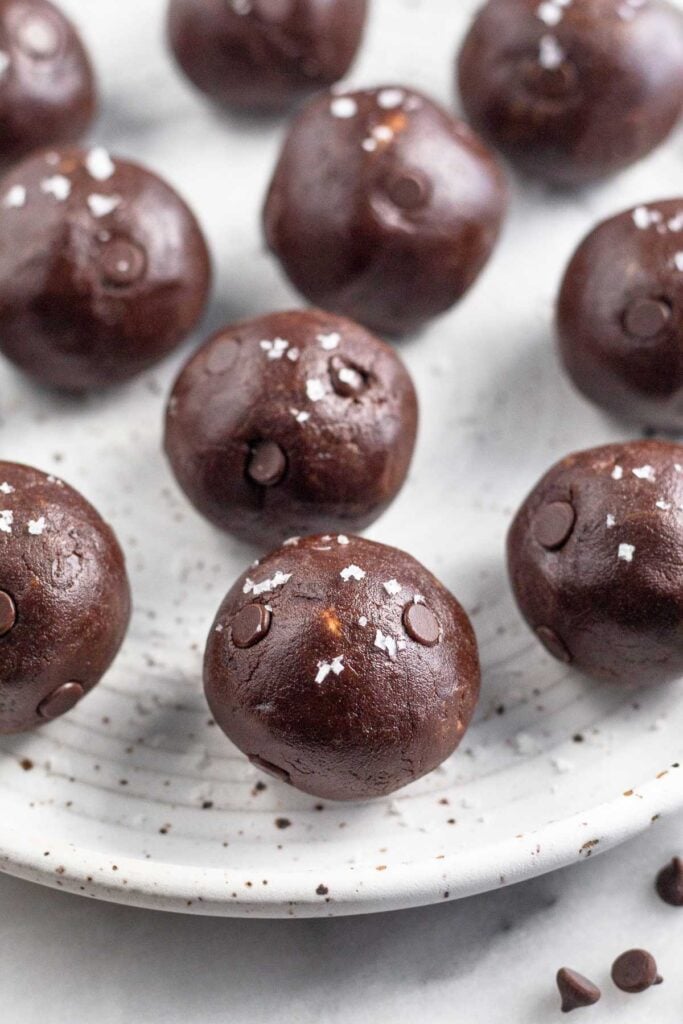 Chocolate protein balls on a white plate. They are sprinkled with sea salt