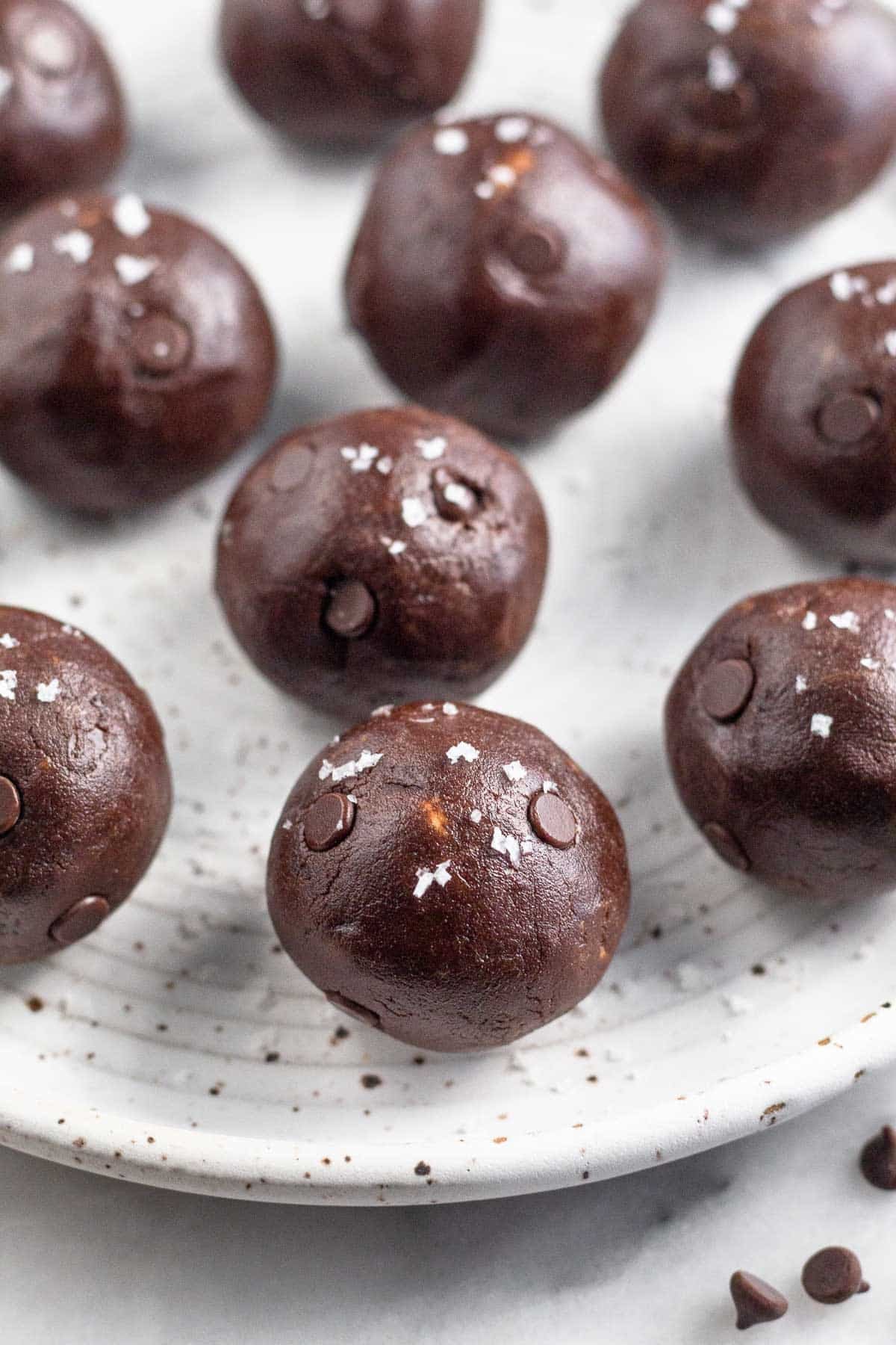 Chocolate protein balls on a white plate. They are sprinkled with sea salt