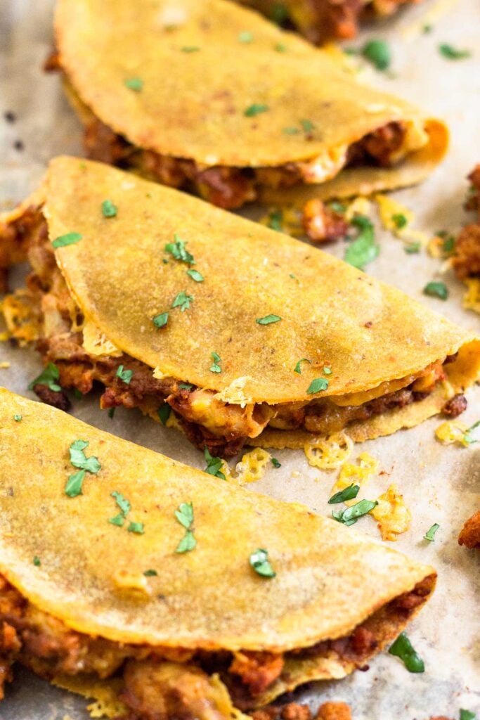 Close up of 3 turkey baked tacos on a baking sheet. They are garnished with cilantro.