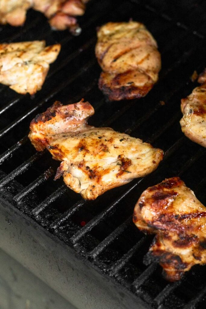 Chicken thighs on a grill being grilled.