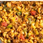 High protein pasta recipe with beef, elbow pasta, veggies, red sauce, and melted cheese on top in a large skillet.