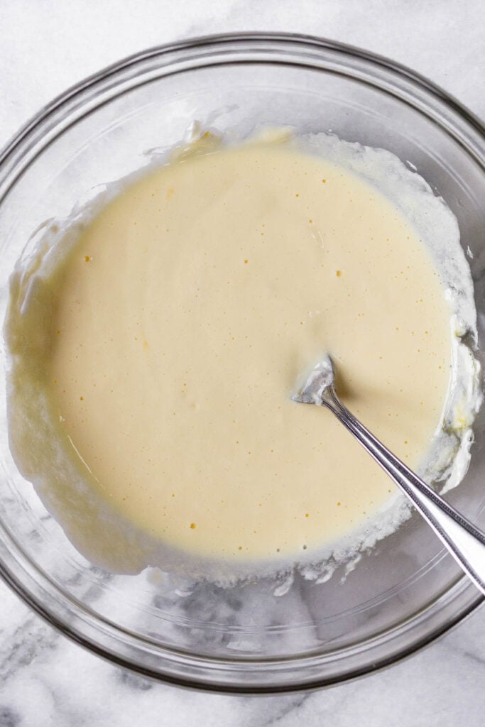 Glass bowl with a wet batter and a fork in it.