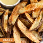 Baked potato wedges piled on a plate with a ramekin of honey mustard.