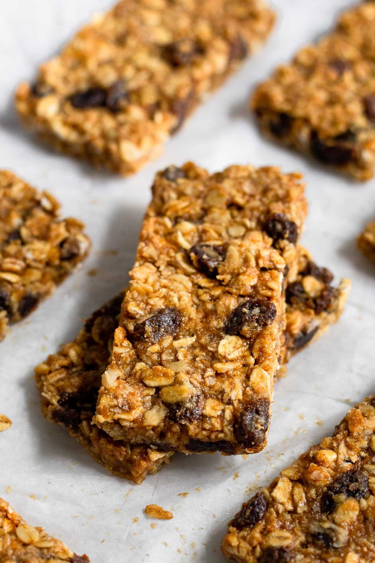 Two oatmeal raisin bars stacked on top of each other with more bars surrounding them.