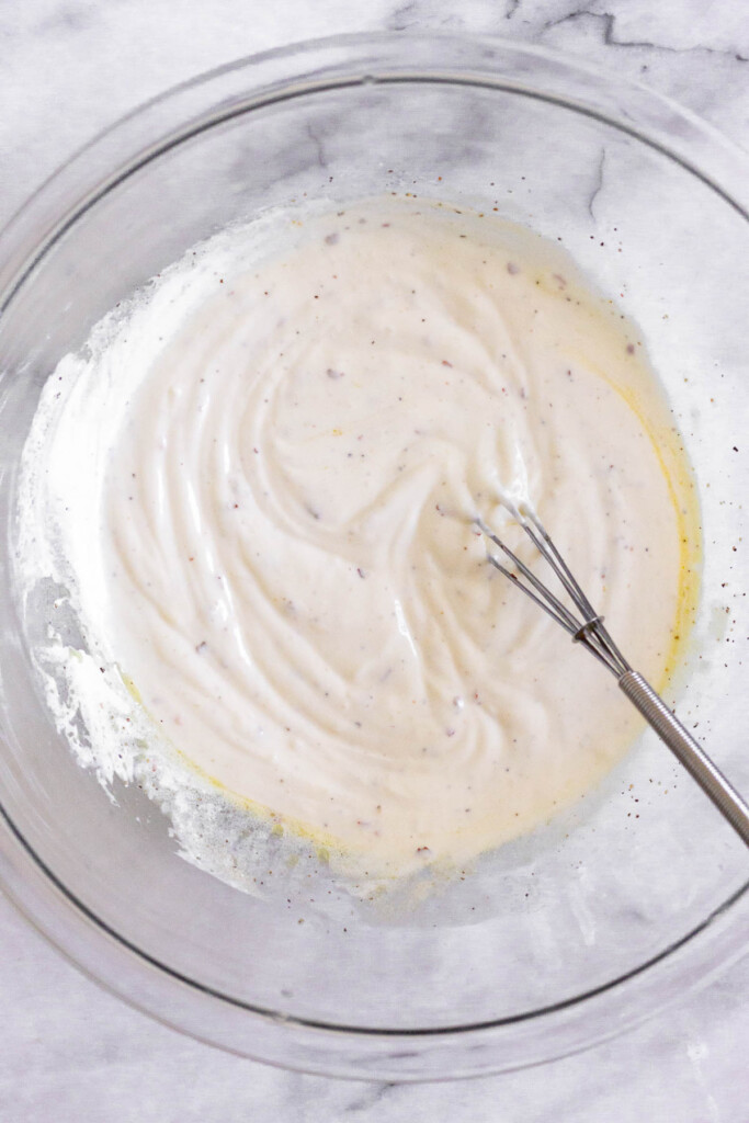A large bowl with a greek yogurt mixture and a small whisk in it.