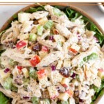 Chicken salad with apples, walnuts, celery, and dates overtop fresh arugula in a bowl.