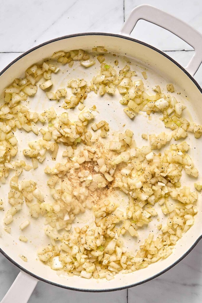 Large white pan with sautéed diced onions.