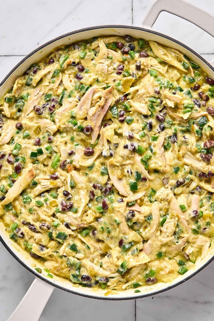 Large while pan filled with a mixture of shredded chicken, veggies, and black beans in a creamy green sauce.