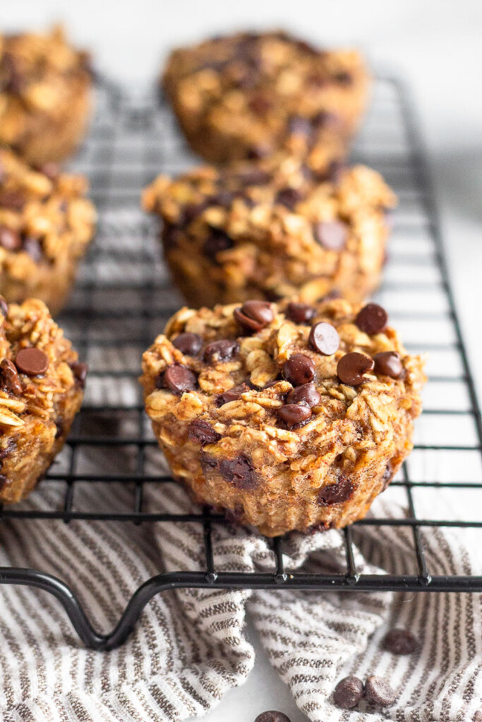 Postpartum oatmeal chocolate chip muffins on a cookie drying rack with a striped towel underneath it.