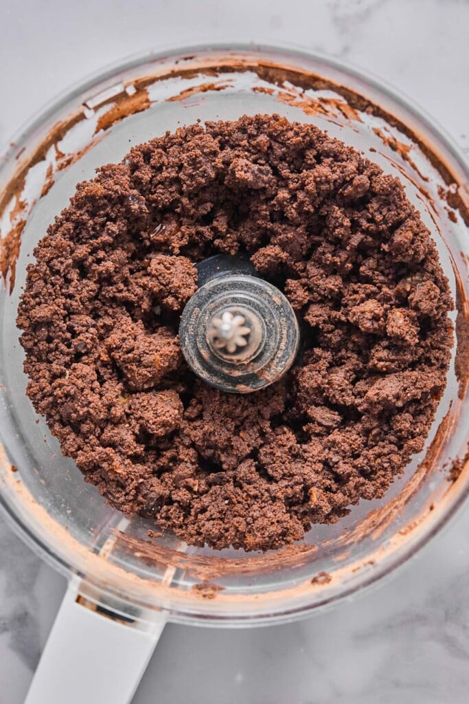 Overhead shot of slightly crumbly but wet chocolate batter in a food processor.