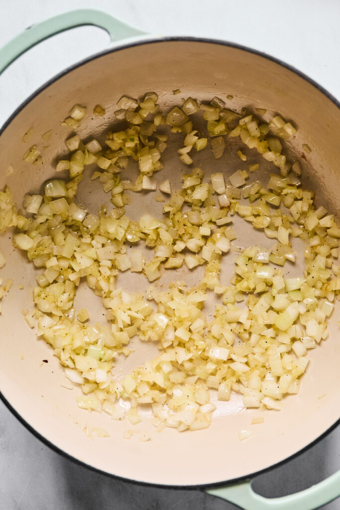 Overhead shot of a large Dutch oven filled with sautéed onions and garlic.
